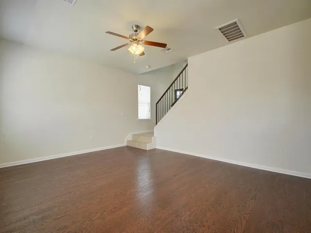 an empty room with wooden floor and fan