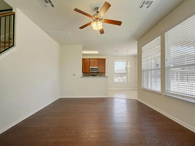 a view of an empty room with a window and wooden floor