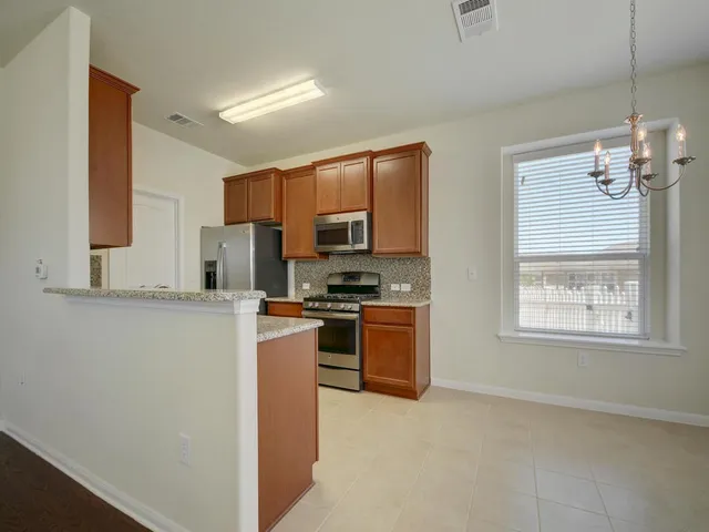 a kitchen with stainless steel appliances granite countertop a stove a sink dishwasher a refrigerator and a microwave oven with white cabinets