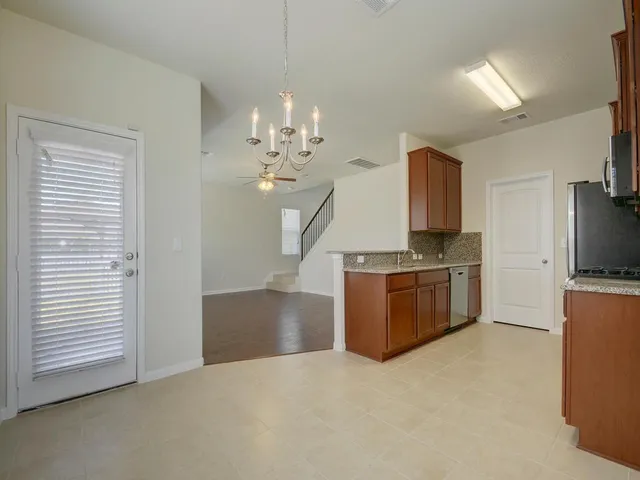 a large kitchen with stainless steel appliances granite countertop a stove oven a sink dishwasher and a refrigerator with wooden floor