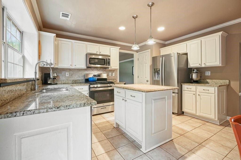 7335 Lytham Trace Cumming, GA 30041 - Photo 12 of 45 a kitchen with kitchen island granite countertop white cabinets white appliances a sink and dishwasher