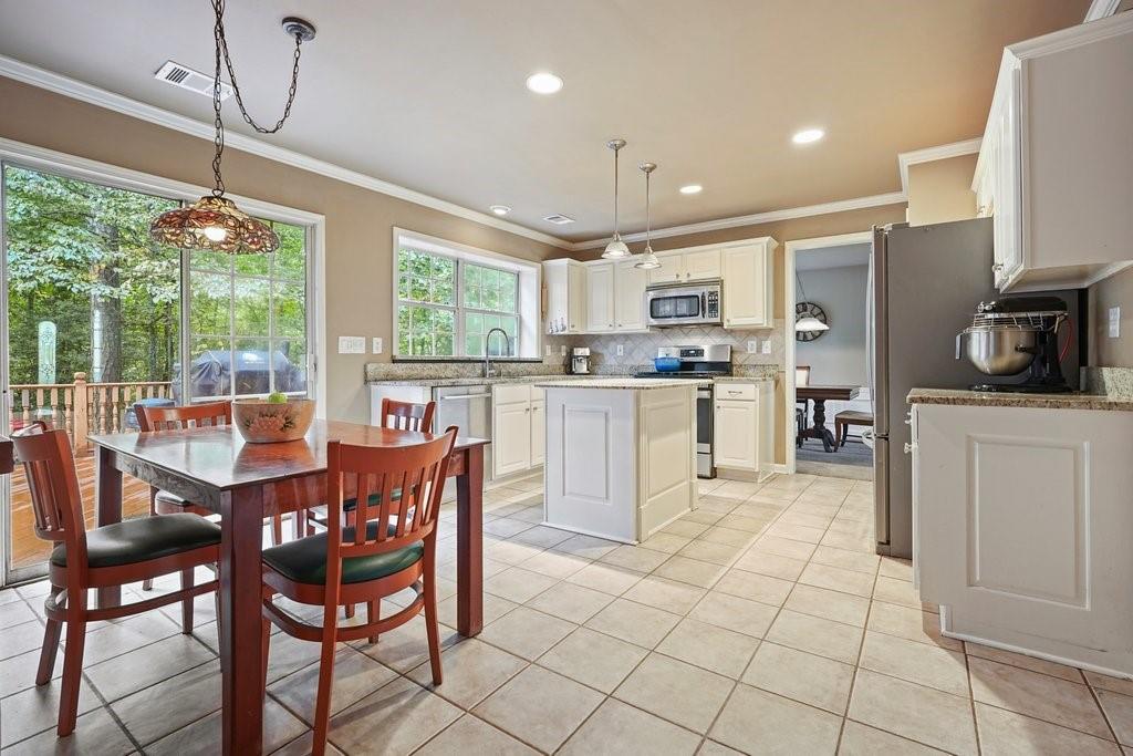 7335 Lytham Trace Cumming, GA 30041 - Photo 7 of 45 a kitchen with stainless steel appliances granite countertop a stove top oven a sink dishwasher a dining table and chairs with wooden floor