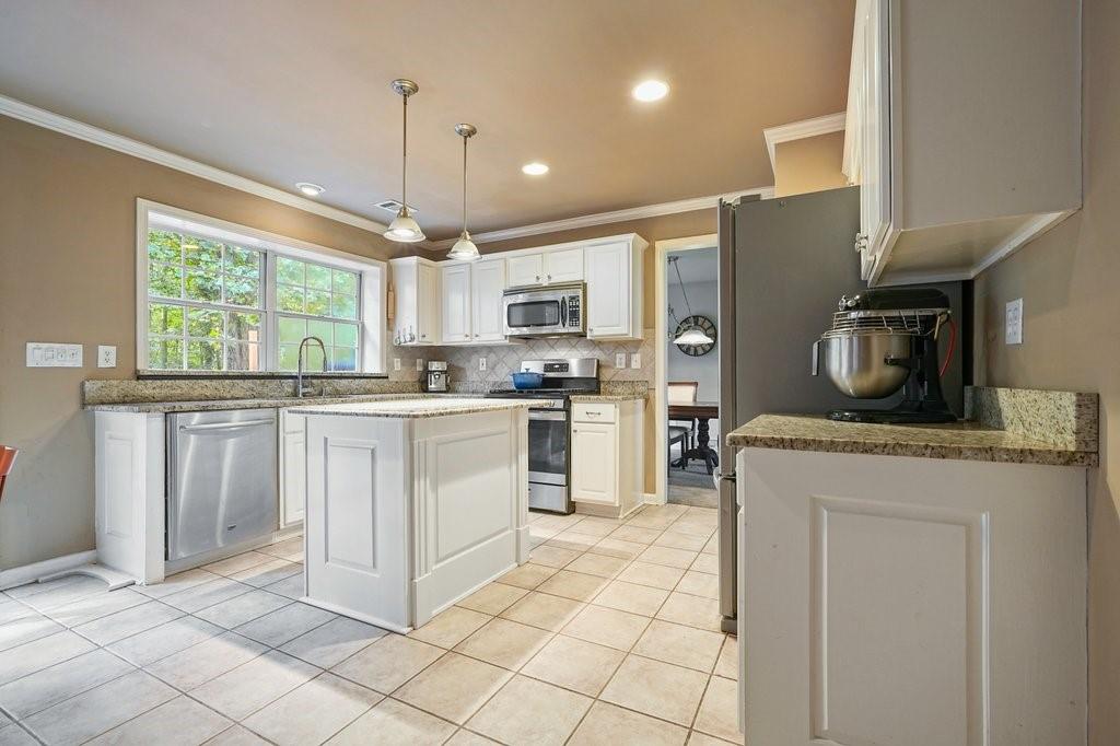 7335 Lytham Trace Cumming, GA 30041 - Photo 8 of 45 a kitchen with kitchen island granite countertop a stove a sink and a refrigerator