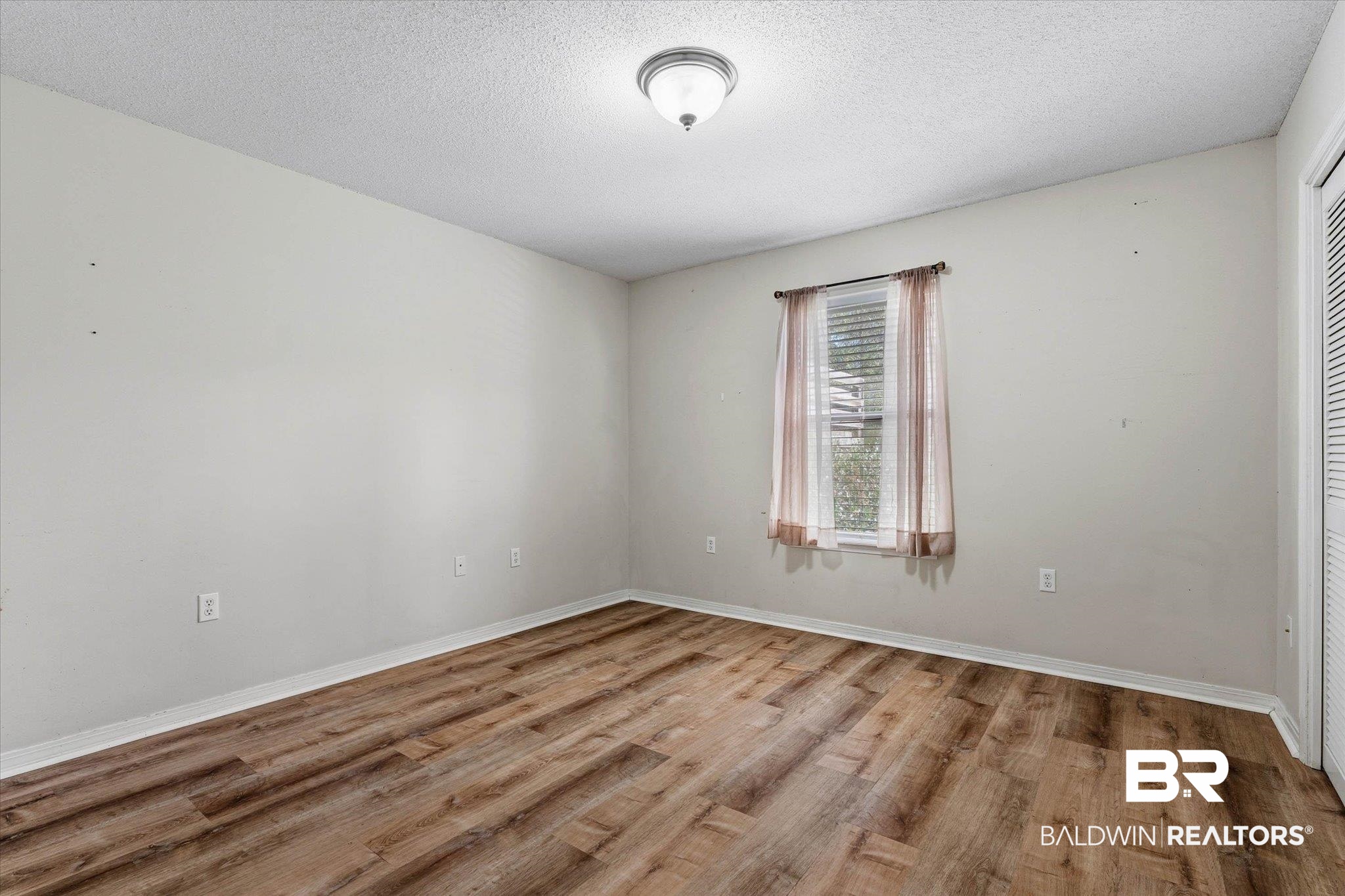 8030 Country Drive Mobile, AL 36619 - Photo 12 of 22 Empty room with light wood-style flooring and a textured ceiling