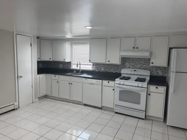 a kitchen with granite countertop white cabinets and white appliances