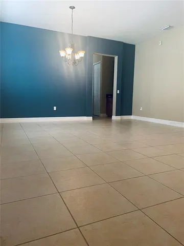 a view of an empty room with chandelier and bathroom