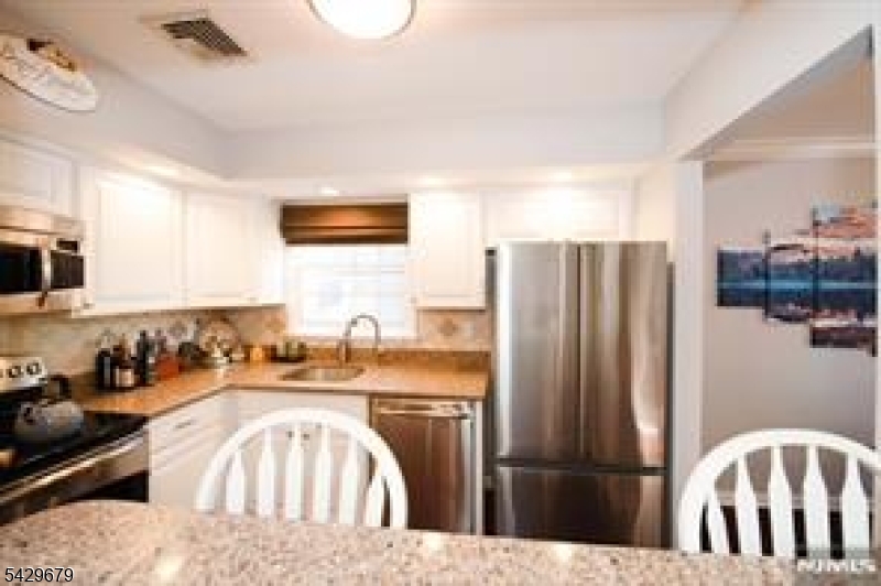 11A South Maple Avenue, Unit B Park Ridge, NJ 07656 - Photo 7 of 16 a kitchen with stainless steel appliances granite countertop a refrigerator a stove a sink and a dining table with wooden floor