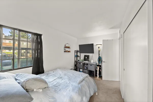 a bedroom with a bed and a flat tv screen on a dresser