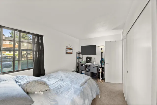 a bedroom with a bed and a flat tv screen on a dresser
