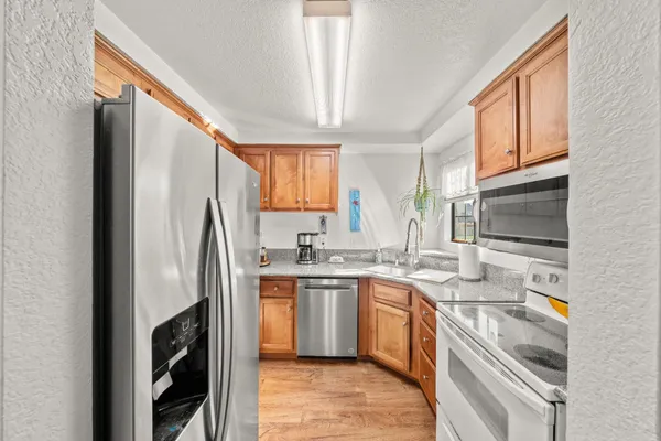 a kitchen with stainless steel appliances granite countertop a refrigerator a stove a sink dishwasher and microwave with cabinets