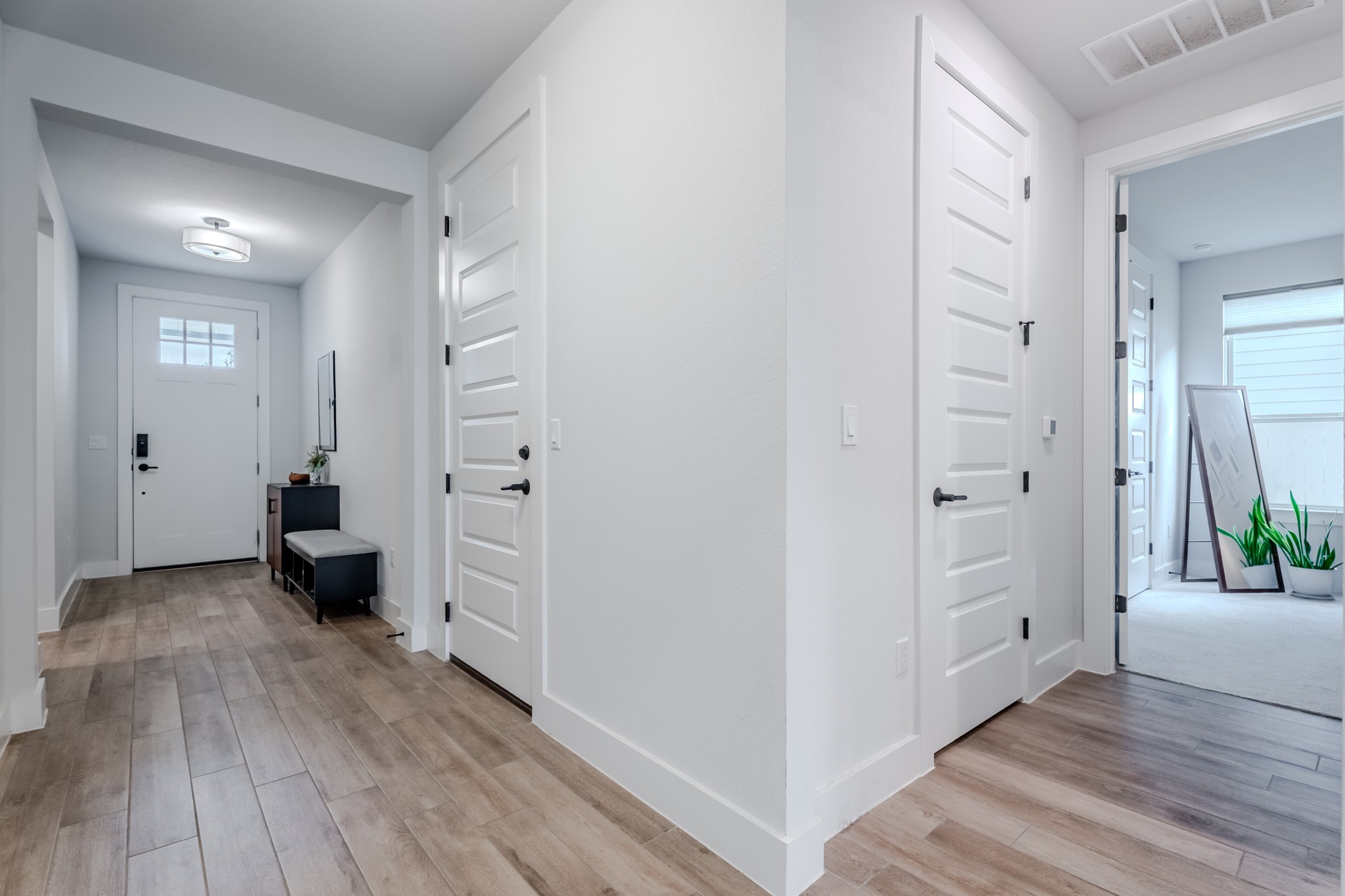 8109 Edmondson Bend Austin, TX 78744 - Photo 7 of 38 A well-lit entry hall with wood plank flooring and multiple white doors leading to various rooms.
