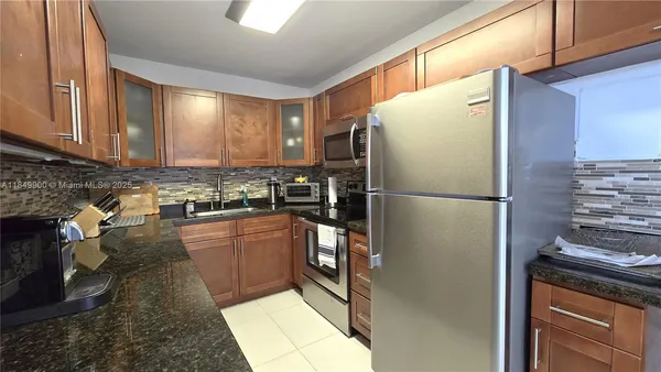 a kitchen with stainless steel appliances granite countertop a refrigerator a stove and a sink