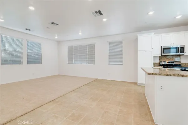a large white kitchen with kitchen island a sink a stove and a refrigerator