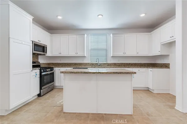 a kitchen with granite countertop a sink stove and cabinets