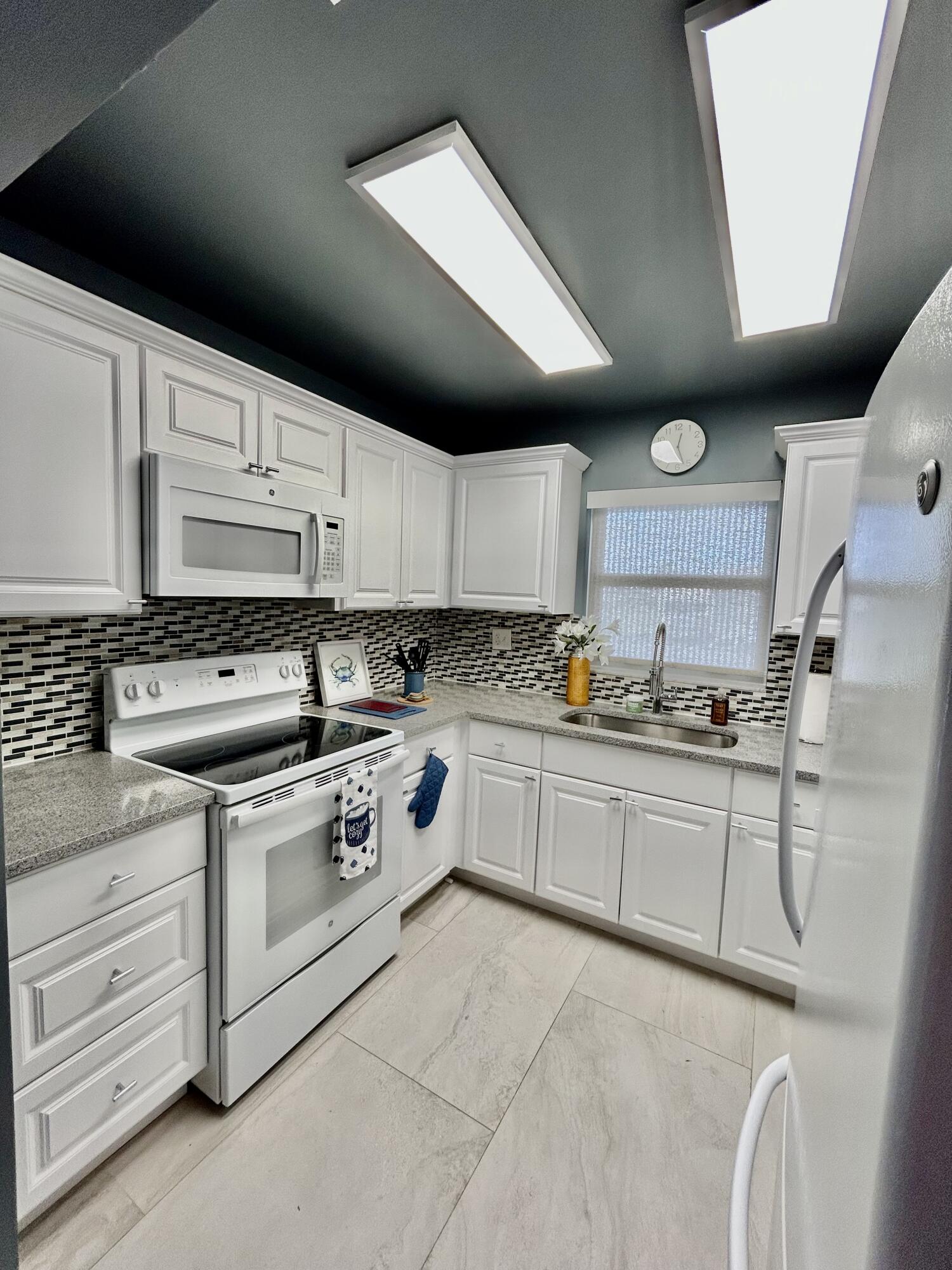 5289 Lake Front Boulevard, Unit D Delray Beach, FL 33484 - Photo 2 of 14 a kitchen with granite countertop a sink stainless steel appliances and cabinets