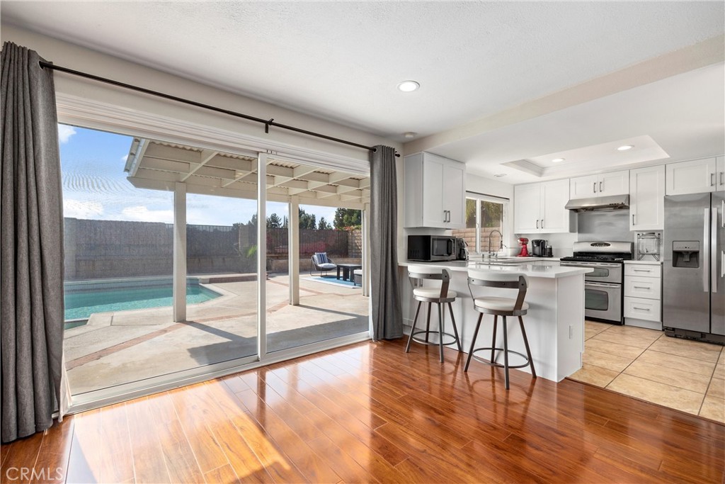 1415 Rolling Knoll Road Diamond Bar, CA 91765 - Photo 8 of 24 a kitchen with stainless steel appliances granite countertop a stove top oven a sink and a dining table with garden view