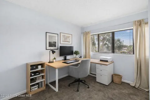 a view of a workspace with furniture and a window
