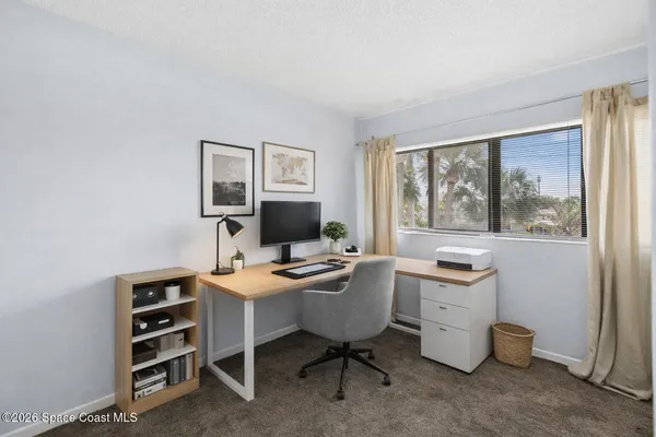 a view of a workspace with furniture and a window