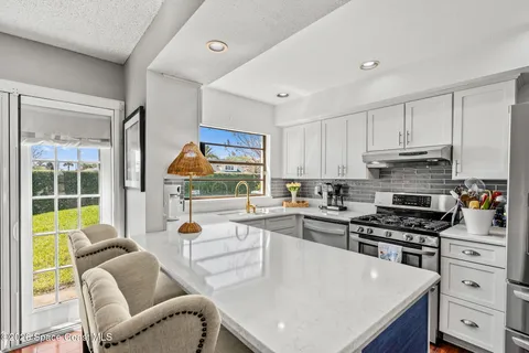 a kitchen with stainless steel appliances granite countertop a stove a refrigerator a kitchen island a stove and white cabinets