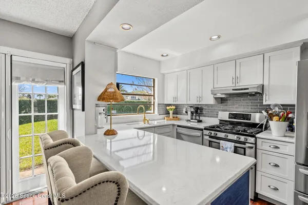 a kitchen with stainless steel appliances granite countertop a stove a refrigerator a kitchen island a stove and white cabinets