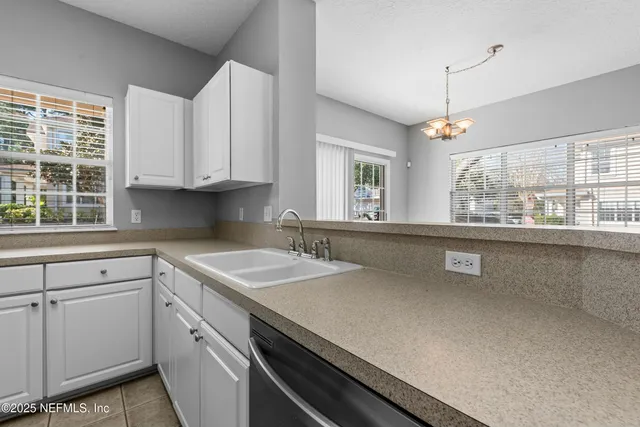 a kitchen with granite countertop a sink and white cabinets
