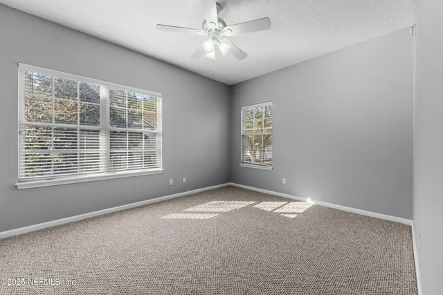 an empty room with windows and fan
