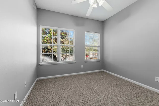 an empty room with windows and chandelier fan