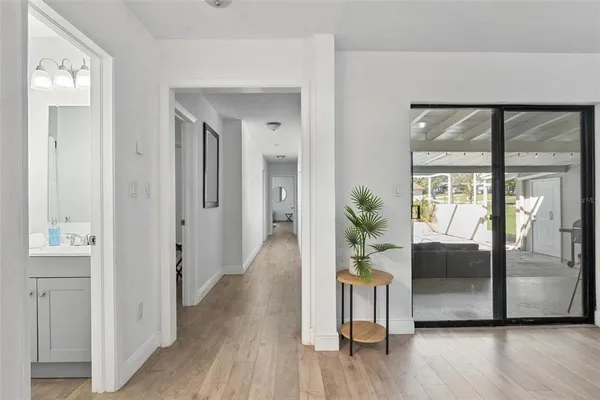 a view of a hallway to a livingroom with wooden floor and a staircase