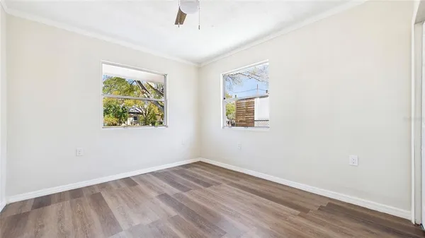an empty room with wooden floor and windows