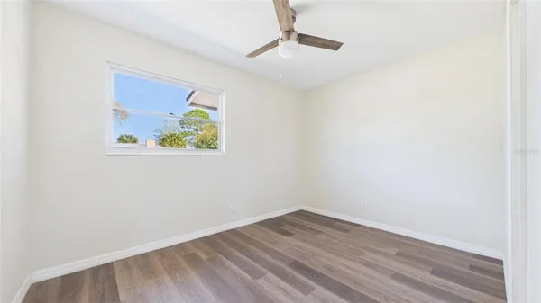 an empty room with wooden floor and ceiling fan