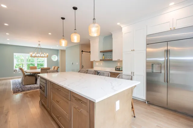 a large kitchen with kitchen island white cabinets and stainless steel appliances