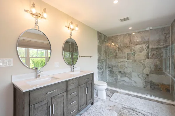 a bathroom with a double vanity sink mirror and toilet
