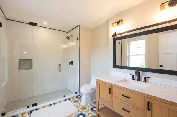 a bathroom with a double vanity sink toilet mirror and shower