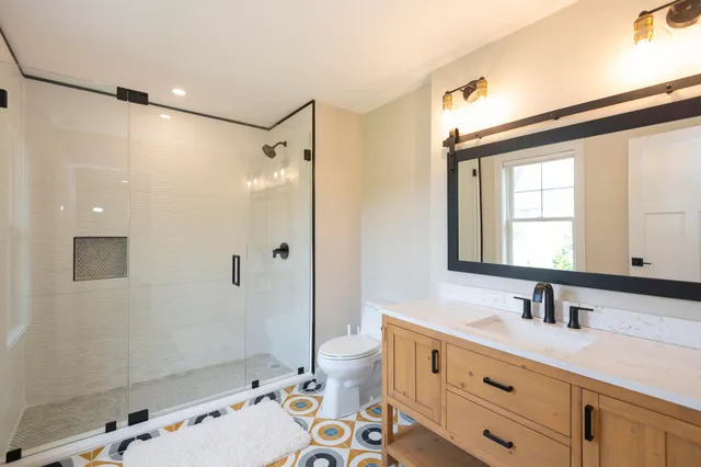 a bathroom with a double vanity sink toilet mirror and shower