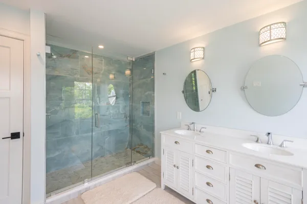 a bathroom with a double vanity sink mirror and shower