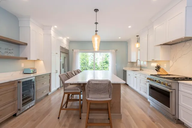 a kitchen with a stove a sink and chairs
