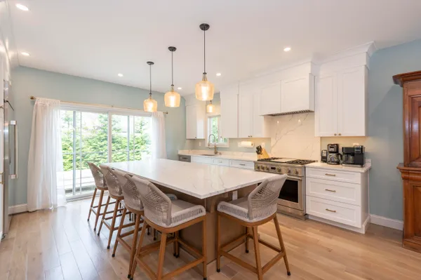 a kitchen with stainless steel appliances granite countertop a stove a refrigerator a kitchen island a table and chairs with wooden floor