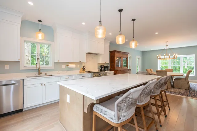 a large kitchen with kitchen island a stove a sink a center island and a wooden floor