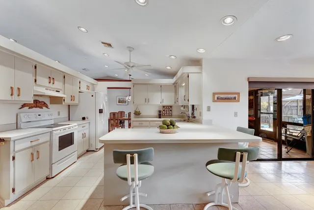 a kitchen with stainless steel appliances granite countertop a stove top oven a sink dishwasher and white cabinets with wooden floor