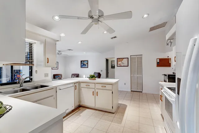 a large white kitchen with stainless steel appliances granite countertop a sink and cabinets