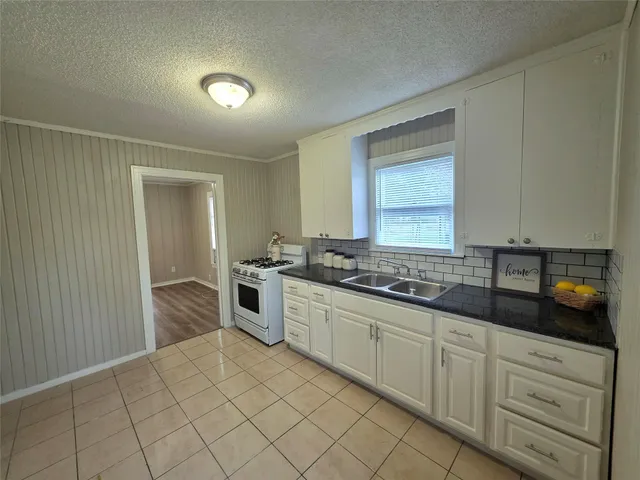 a kitchen with white cabinets and sink