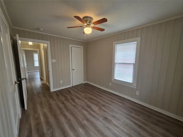 an empty room with wooden floor and a ceiling fan
