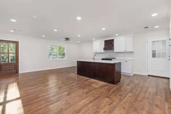 a large kitchen with kitchen island a sink dishwasher a stove and a refrigerator with wooden floor