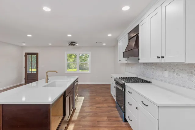 a kitchen with granite countertop white cabinets sink and stainless steel appliances