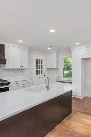 a large kitchen with stainless steel appliances a large counter top a stove and a refrigerator