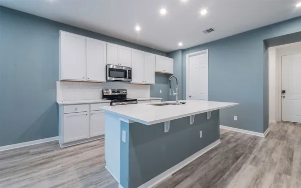 a kitchen with kitchen island granite countertop a sink and a stove top oven