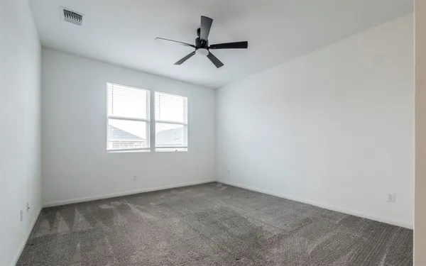 an empty room with ceiling fan and windows