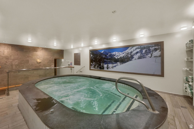 50 Shadow Ridge Road, Unit 4209 Park City, UT 84060 - Photo 36 of 50 Indoor pool with integrated steps and handrails, stone accent wall, recessed lighting, and wood-finish flooring