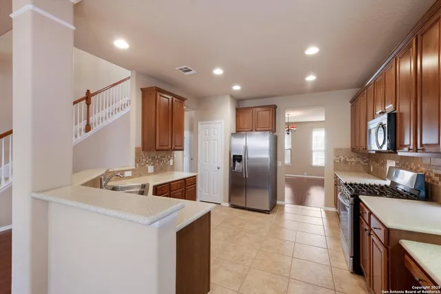 a kitchen with stainless steel appliances granite countertop a sink a stove and a refrigerator