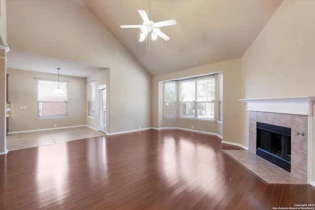 a view of an empty room with wooden floor fireplace and a window